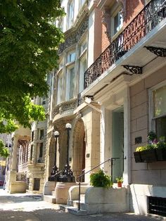 an apartment building on the corner of a street with potted plants in front of it