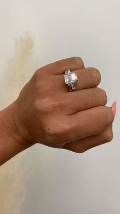 a woman's hand holding an engagement ring in her left hand, with the diamond set on top