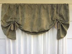 a curtain with tassels hanging from it's side in front of a window