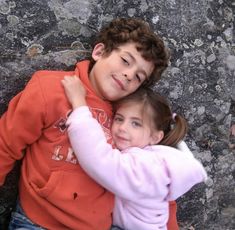 two young children hugging each other on the ground