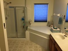 a bathroom with a sink, shower and two windows in the room that are open