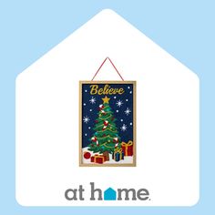 a christmas tree hanging from the side of a house with an at home sign above it