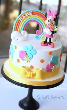 a birthday cake decorated with minnie mouse and rainbow