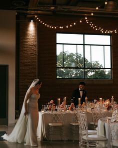 a bride and groom standing in front of a table set for their wedding reception at the loft