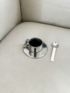 there is a cup and spoon on the back of a couch next to a bottle opener