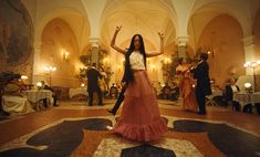 a woman in a long skirt is dancing on the dance floor with other people around her