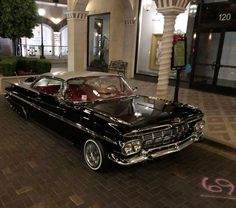 an old black car parked in front of a building