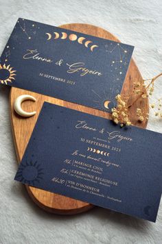 the wedding stationery is laid out on a wooden platter with moon and crescent designs