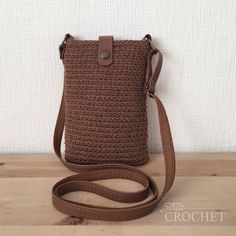 a brown crocheted purse sitting on top of a wooden table