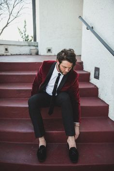 a man in a suit and tie sitting on some steps with his feet up to the ground