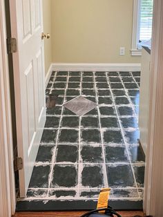 an empty room with black and white tiles on the floor in front of two doors