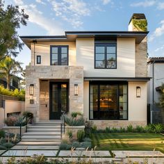 a modern home with stone and black trim on the front door, steps leading up to it