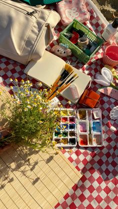 the picnic table is full of art supplies and flowers, such as watercolors