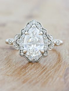 an oval shaped diamond ring on top of a wooden table