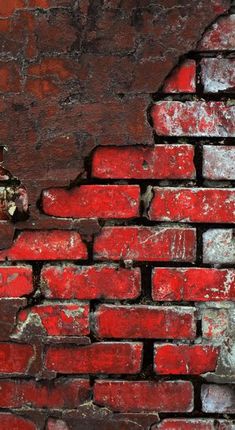 an old red brick wall with peeling paint and chipped paint on the bricks is shown