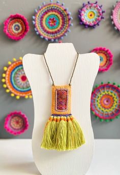 the necklace is decorated with multicolored beads and tassels on a white mannequin