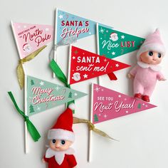 a group of small christmas flags on top of a white table next to a toy elf