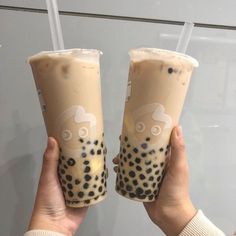 two people holding up drinks in front of a glass wall with an octopus on it