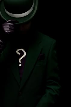 a man wearing a green suit and hat with a question mark on his chest in front of him