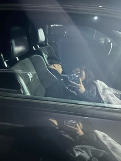 a woman sitting in the back seat of a car holding a cell phone