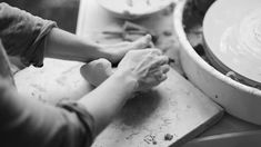 two people are working on pottery in a potter's wheel, with their hands resting on the bowl