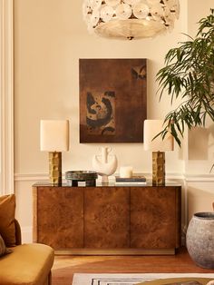 a living room filled with furniture and a painting hanging on the wall above it's sideboard