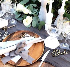 the table is set with silver and white place settings, napkins, wine glasses, and flowers