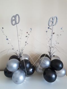 black and silver balloons are sitting on a table with the number six in front of them