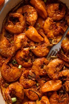 a pan filled with cooked shrimp and carrots, garnished with a fork