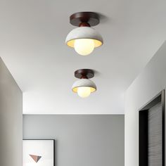 three lights that are hanging from the ceiling in a room with white walls and flooring