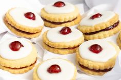 small cookies with white icing and cherry toppings