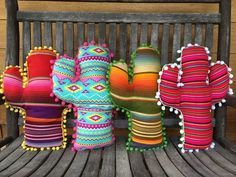 colorful pillows are sitting on a bench with pom poms in the shape of cactuses