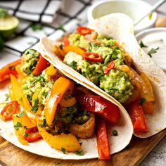 two tacos on a plate with guacamole and peppers