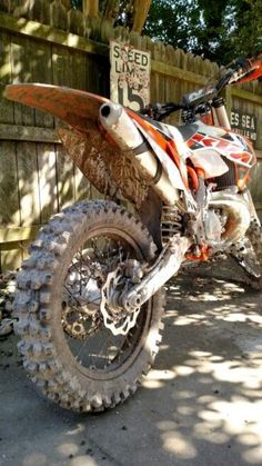 a dirt bike parked in front of a wooden fence