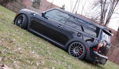 a black minivan parked on top of a lush green field