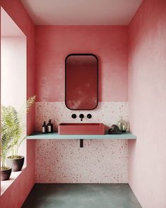 a bathroom with pink walls and white counter tops, in the middle of a room