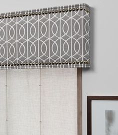 a blue and white window valance hanging on the side of a wall next to a framed photograph