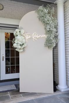 a white sign that says the hawaiian with some flowers on it in front of a building