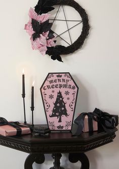 a table topped with a pink and black christmas ornament next to two candles