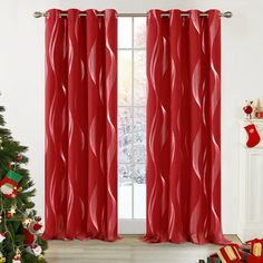 a christmas tree in front of a window with red curtains