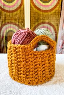 an orange crocheted basket with yarn in it