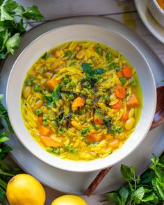 a white bowl filled with soup next to lemons and parsley