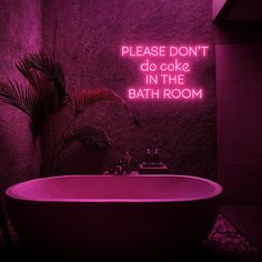 a bath tub sitting next to a plant in a bathroom under a neon sign that reads, please don't do cake in the bath room