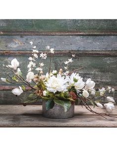 a vase filled with white flowers on top of a wooden table