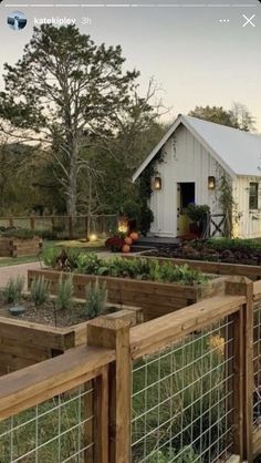 a fenced in garden area with several wooden planters and a small white house