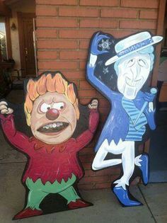 two cartoon characters are standing next to each other on the sidewalk in front of a brick building