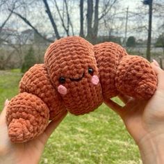 a hand holding a small crocheted stuffed animal in the shape of a caterpillar