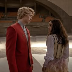 a man and woman standing next to each other in front of an empty stadium area