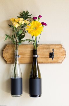 two vases with flowers in them are hanging on a wall mounted coat hanger