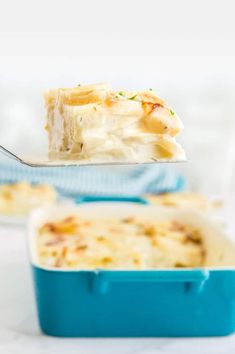 a piece of casserole being lifted from a blue dish with a spoon in it